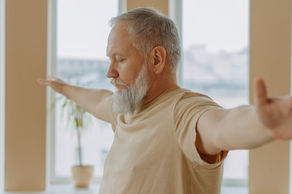 Person stretching gently near a large window.
